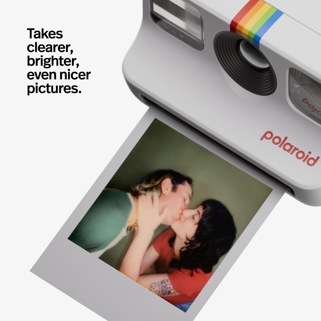 Polaroid camera with a printed photo of two people kissing, featuring text 'Takes clearer, brighter, even nicer pictures.'