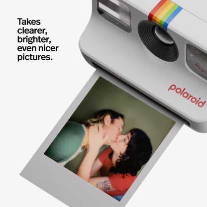 Polaroid camera with a printed photo of two people kissing, featuring text 'Takes clearer, brighter, even nicer pictures.'