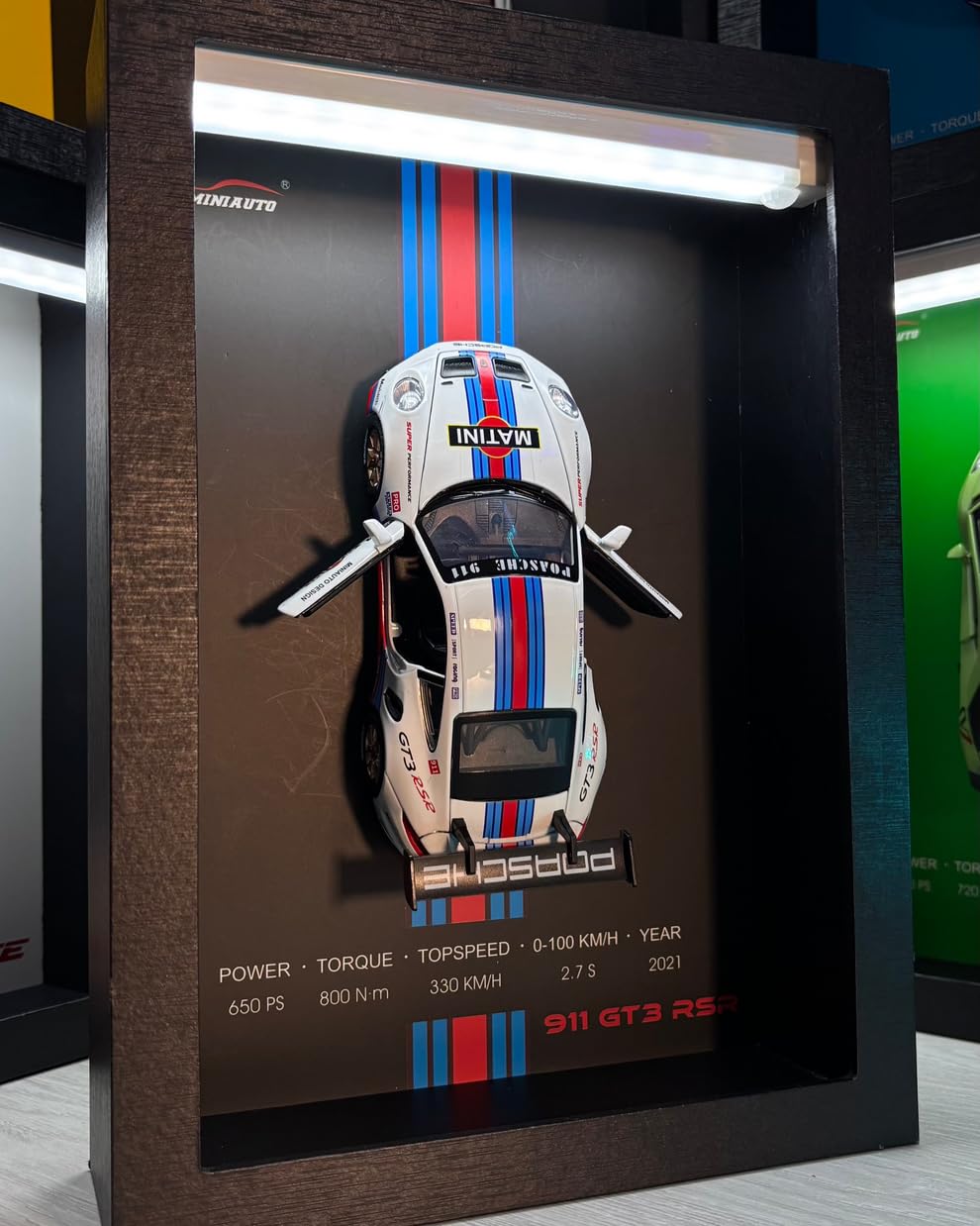 Close-up of Toy Rush 3D car frame with realistic die-cast cars and glowing LED lights in a wooden display case.