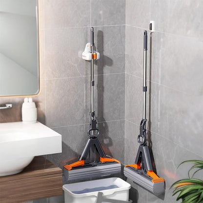 Two mops with orange accents leaning against a tiled bathroom wall.