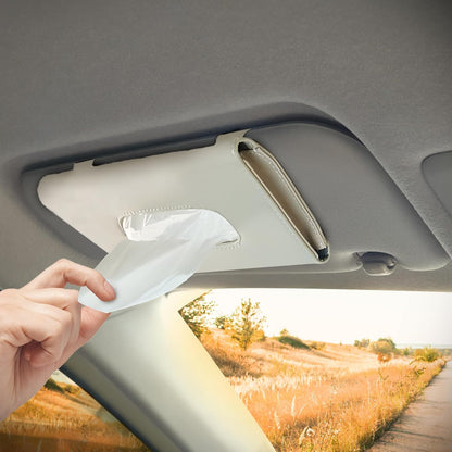Hand reaching for a tissue in a car's sun visor with a scenic background